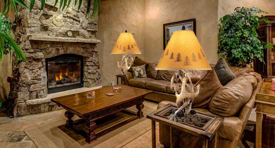 Mountain Lodge Style Living Room with Stone Fireplace, Leather Couches and Antler Lamps